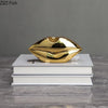 A gold faux finish human body resin art sculpture resting on a stack of white books.