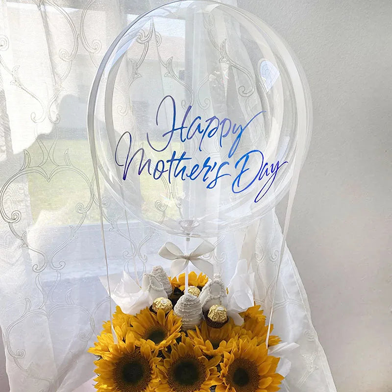 A clear balloon arch featuring blue script that reads Happy Mother's Day surrounded by a bouquet of yellow sunflowers.