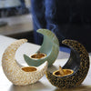 A set of antique crescent resin incense burners in cream and gold colors resting on a white surface.