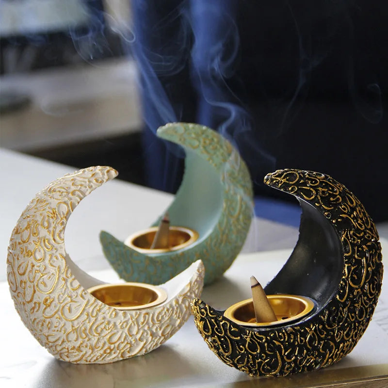 A set of antique crescent resin incense burners in cream and gold colors resting on a white surface.