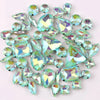 A mix of silver claw setting glass rhinestones in jelly candy AB colors scattered on a white background.
