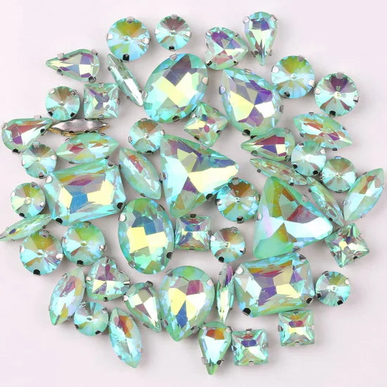 A mix of silver claw setting glass rhinestones in jelly candy AB colors scattered on a white background.