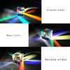 A clear optical glass prism cube is shown refracting light into a rainbow spectrum on a dark surface.