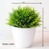 A vibrant green artificial bonsai tree in a white pot, shown from above.