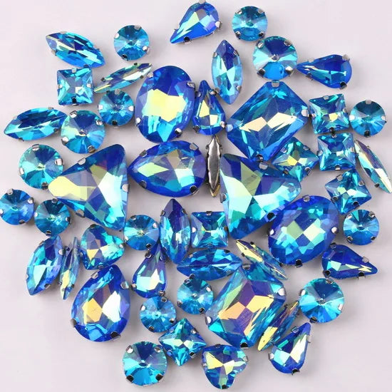 A collection of blue and clear glass rhinestones in various shapes and sizes set in silver claws.
