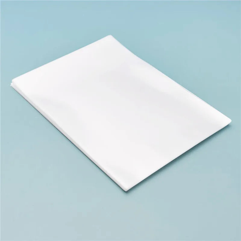 A white cellophane gift bag with a gold twist tie lying on a light blue surface.
