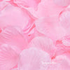 Pink silk rose petals scattered on a surface for weddings and events.