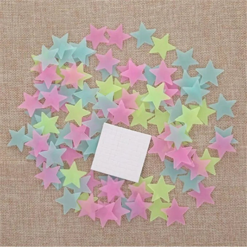 A collection of 50 glow-in-the-dark star wall stickers in various pastel colors scattered on a beige fabric background.