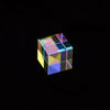 A transparent optical glass cube prism displaying various light refractions and colors against a black background.