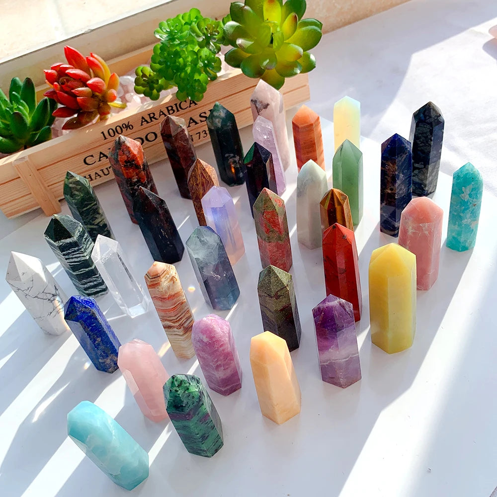 A collection of natural crystal point prisms in various colors arranged on a white surface.