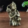 Bronze Hanuman statue figurine of a monkey god seated in a meditative pose on a wooden surface.