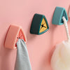 Pink and teal suction cup towel holders mounted on a wall, with a gray towel hanging from one.