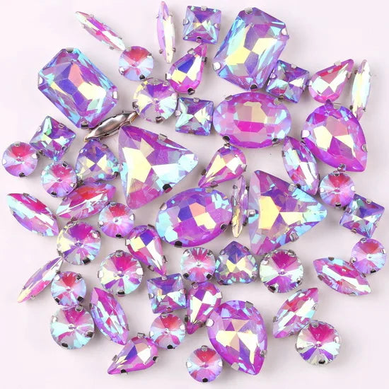 A mix of silver claw setting glass rhinestones in jelly candy AB colors scattered on a white background.