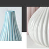 A white ceramic vase with vertical ribbed texture, shown in a close-up view.