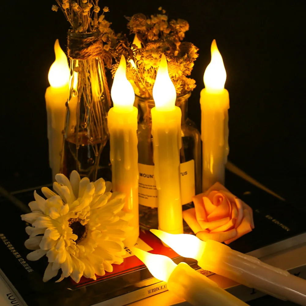 A collection of glowing yellow LED taper candles and a single orange rose displayed against a dark background.