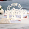 Gold pearl laser cut wedding invitations featuring a white floral arch and silhouette design