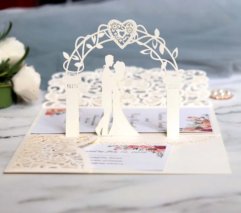 Gold pearl laser cut wedding invitations featuring a white floral arch and silhouette design
