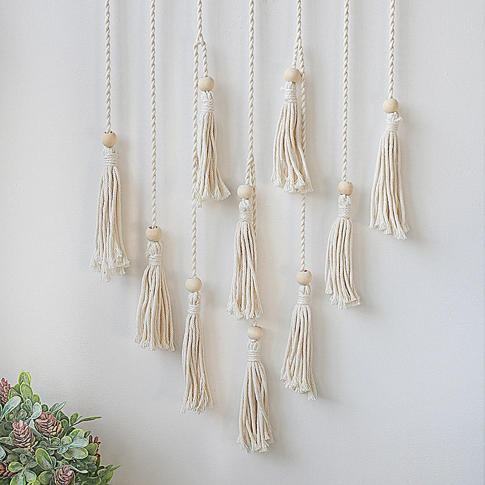 Boho macrame photo display featuring multiple cream-colored tassels hanging on a white wall
