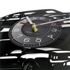 A black vinyl record sports car wall clock with a white face and gold-colored hands.