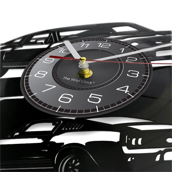 A black vinyl record sports car wall clock with a white face and gold-colored hands.