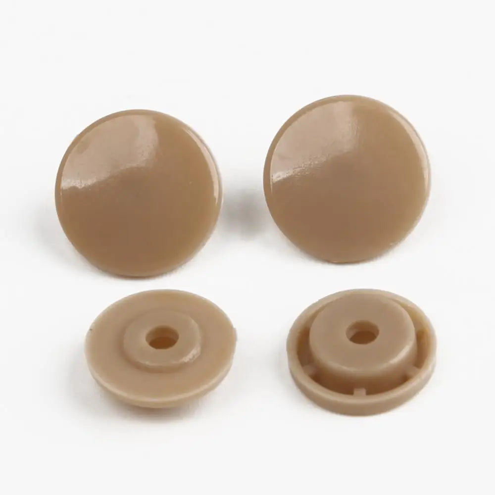 Four round, light tan snap buttons of different sizes for crafting.