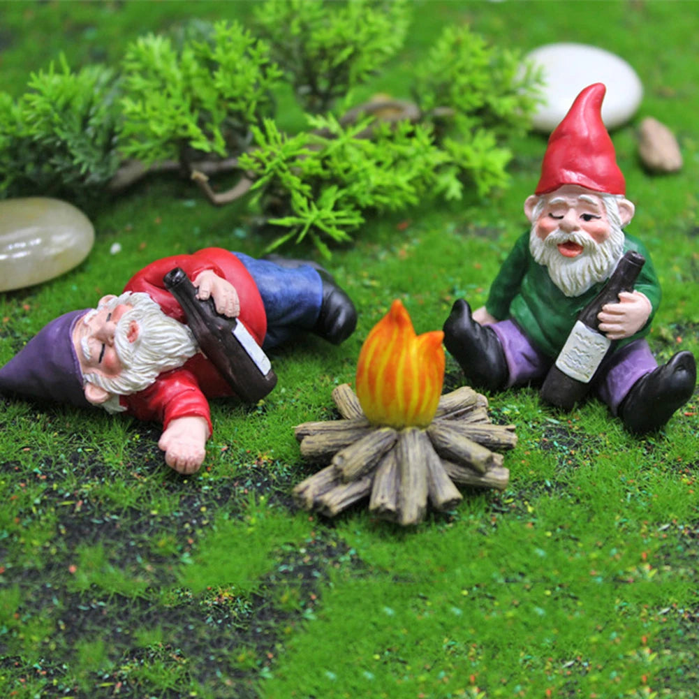 A miniature resin gnome statue with a red hat and white beard lying on green moss with a bottle.