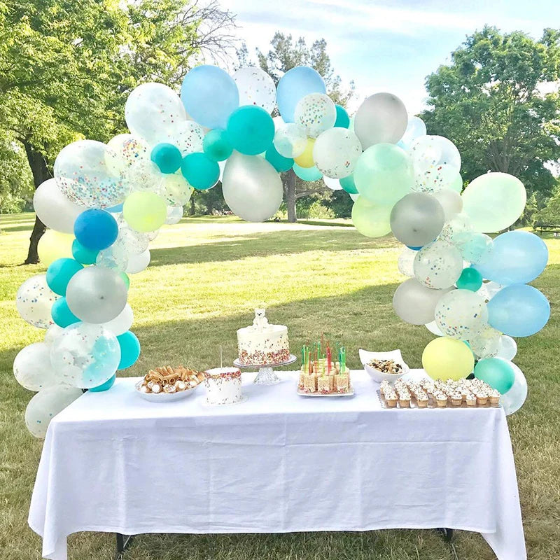 A balloon arch decoration featuring a mix of light blue, teal, and white balloons set up outdoors for an event.