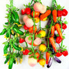 A vibrant arrangement of lifelike artificial fruits and vegetables including tomatoes, carrots, and peppers on a green vine.