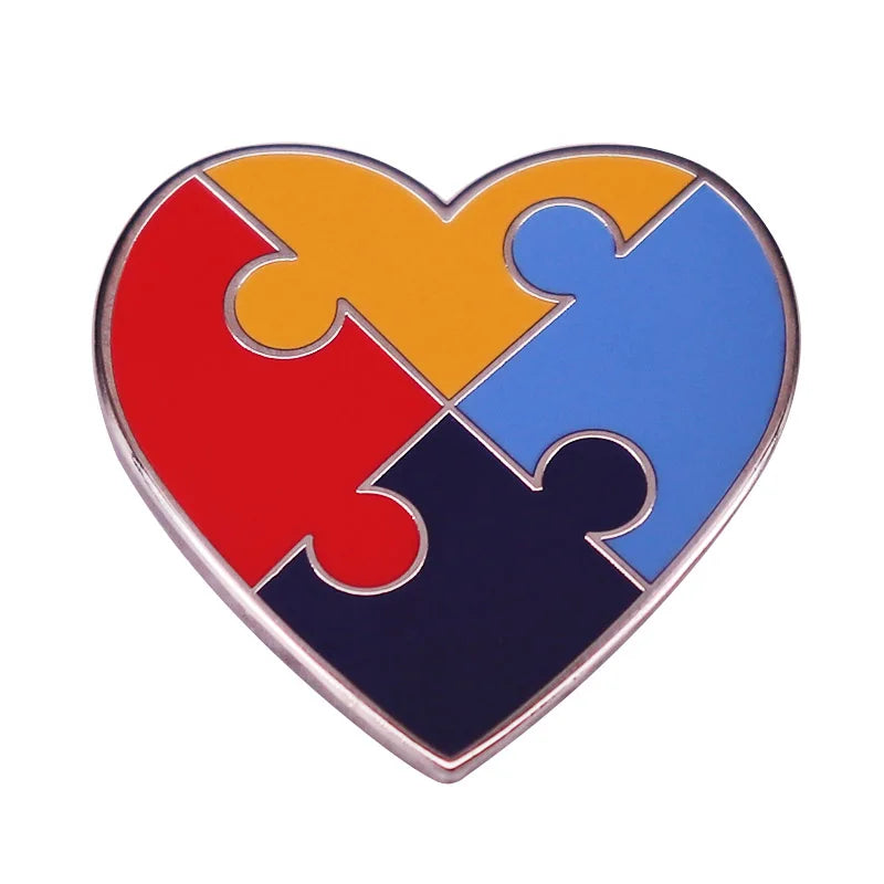 A heart-shaped puzzle piece brooch pin featuring rainbow colors of red, orange, yellow, blue, and purple.