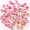 A mix of silver claw setting glass rhinestones in jelly candy AB colors scattered on a white background.