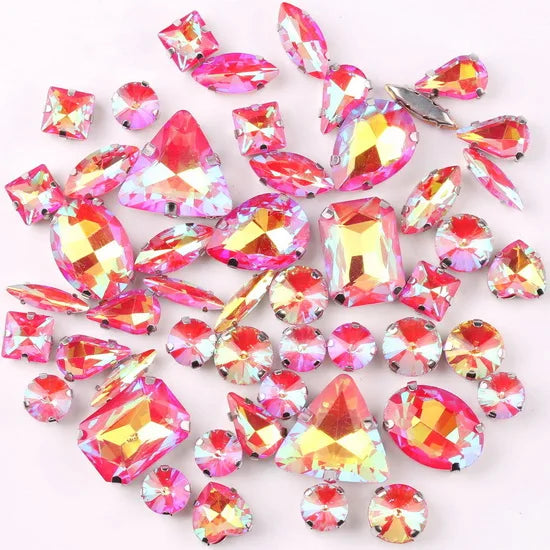 A mix of silver claw setting glass rhinestones in jelly candy AB colors scattered on a white background.