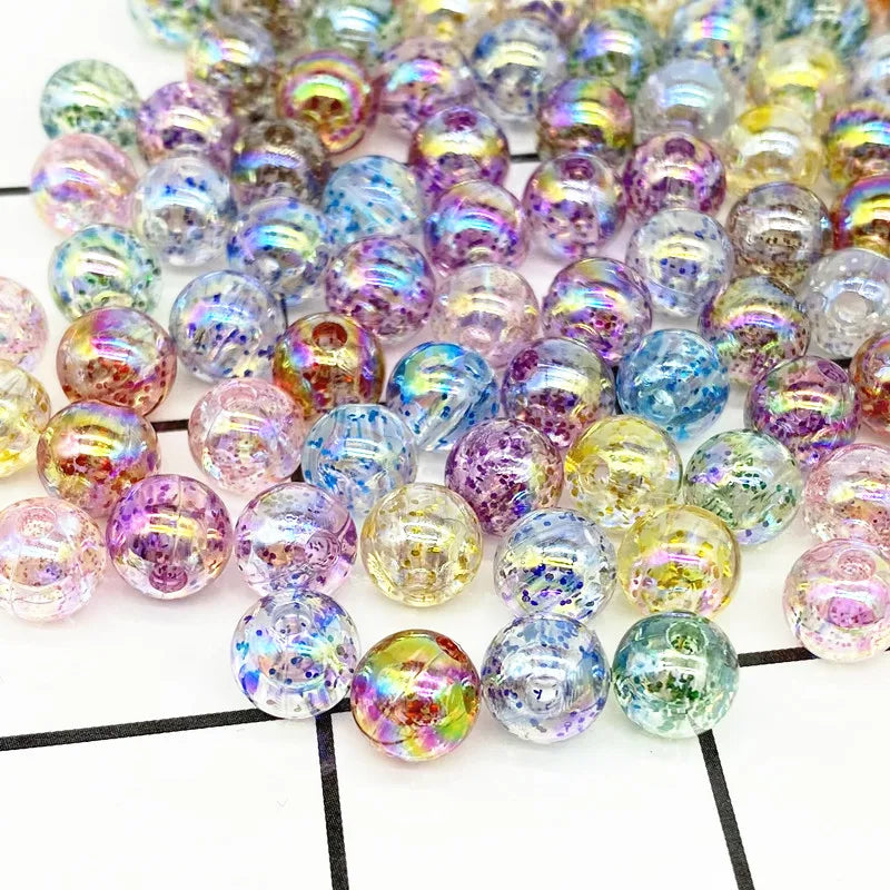 A pile of iridescent acrylic round beads in various shades of purple, blue, and green for jewelry making