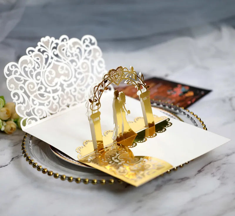 Gold pearl laser cut wedding invitations featuring intricate white lace and gold accents on a white card.