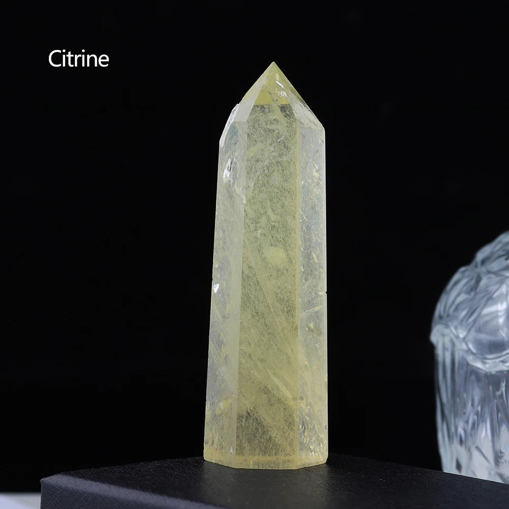 A clear yellow citrine crystal point prism tower displayed on a dark surface.