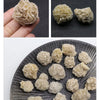 A collection of natural desert rose selenite stones in various sizes and textures displayed on a dark slate surface.