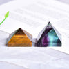 Dos cristales de pirámide de fluorita natural, uno ámbar y otro verde-morado, sobre una superficie blanca.