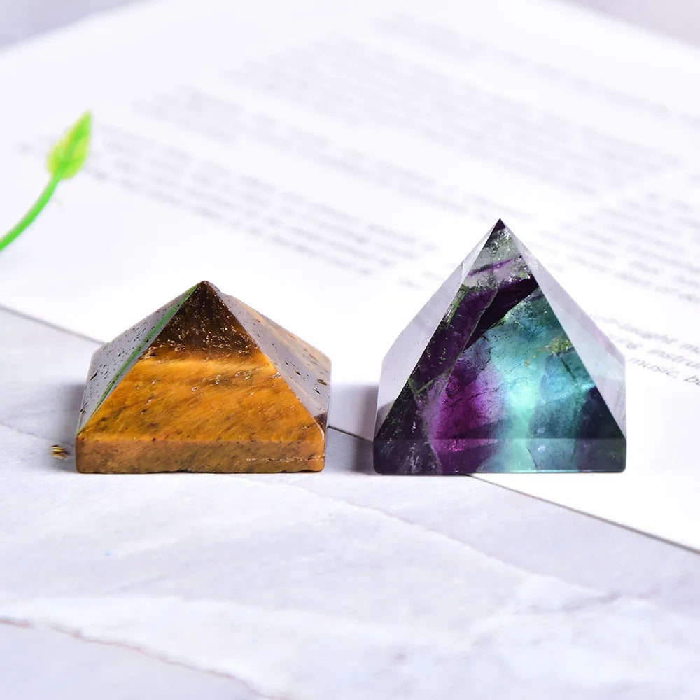 Dos cristales de pirámide de fluorita natural, uno ámbar y otro verde-morado, sobre una superficie blanca.