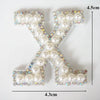 A white alphabet letter X made of pearl and iridescent rhinestones.