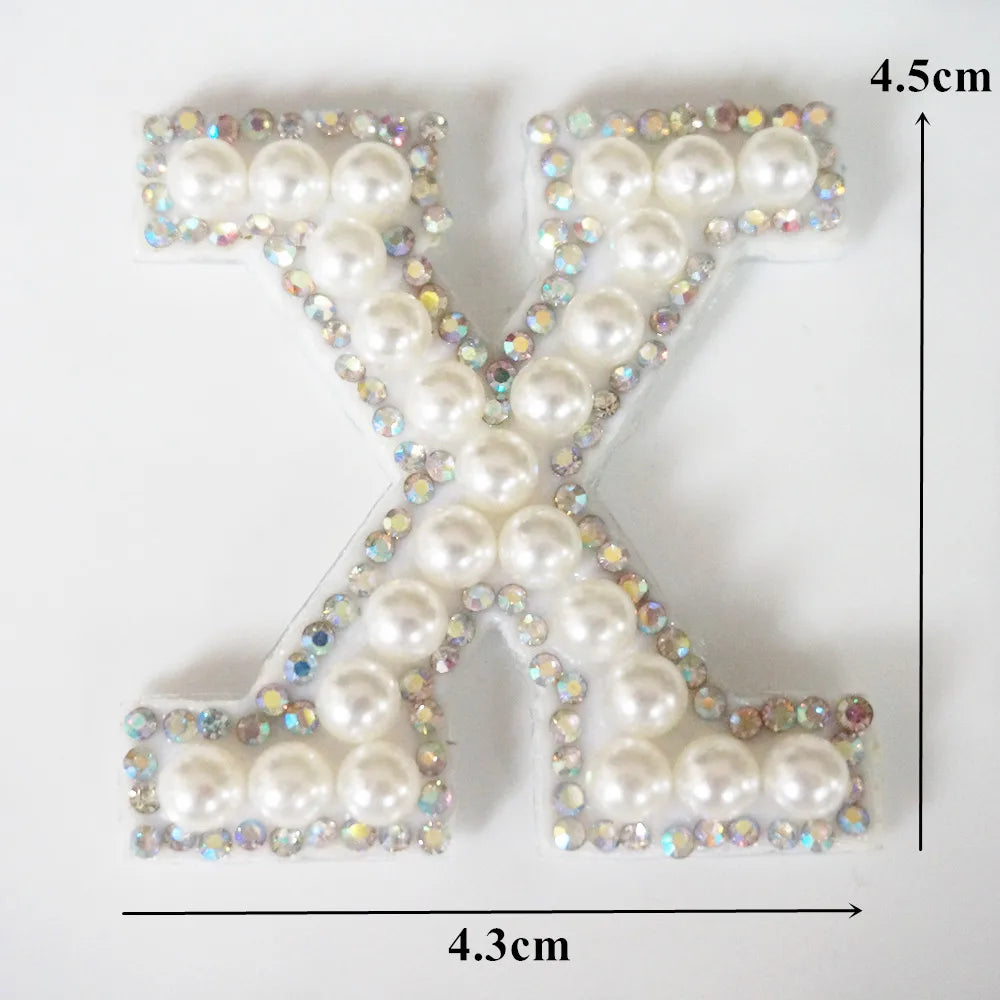 A white alphabet letter X made of pearl and iridescent rhinestones.