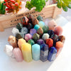 A collection of natural crystal point prisms in various colors arranged on a wooden tray.