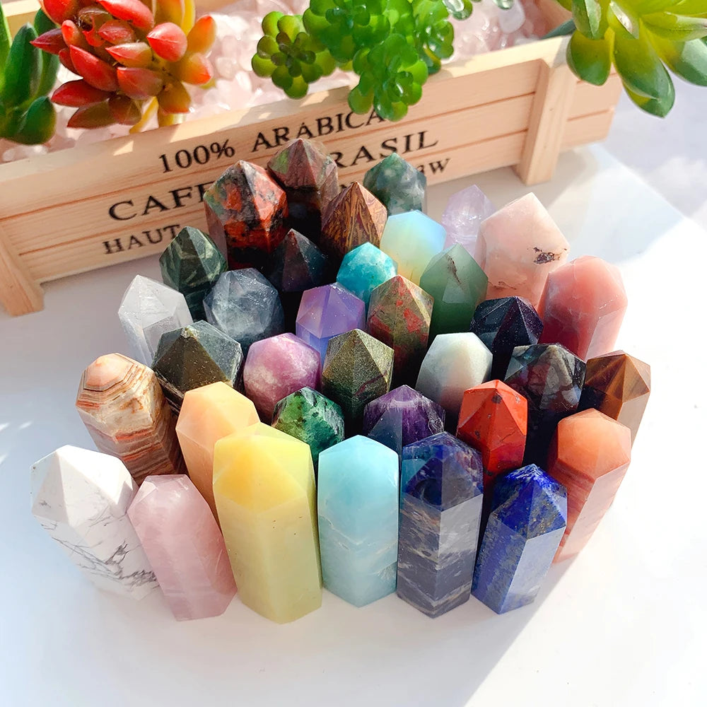 A collection of natural crystal point prisms in various colors arranged on a wooden tray.