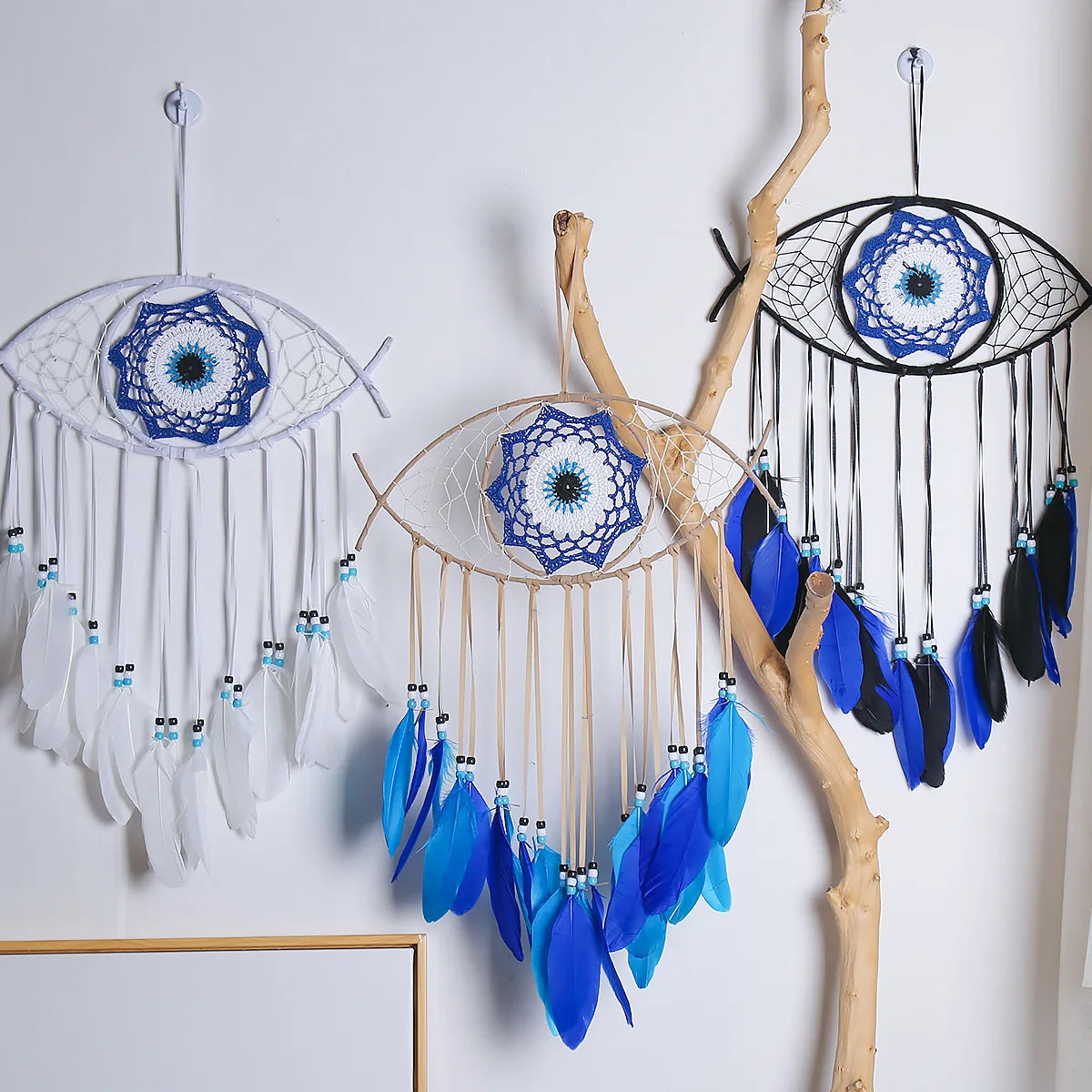 Handmade boho evil eye dream catcher wall decor featuring white and blue feathers and beads hanging on a natural branch