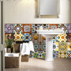 A white pedestal sink with colorful Moroccan tile backsplash and a mirror above it.