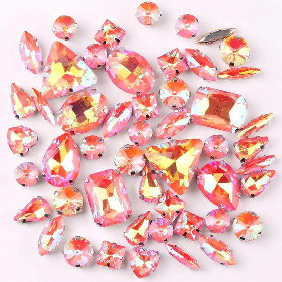 A mix of silver claw setting glass rhinestones in jelly candy AB colors scattered on a white background.