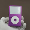 Une main tient un kit de réparation du panneau avant d'un iPod Classic violet avec un bouton de menu circulaire visible.