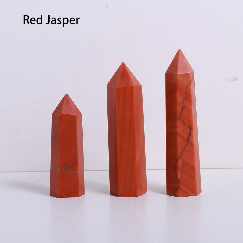 A set of three red jasper crystal point prisms or towers displayed on a white surface.