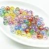 A collection of multicolored acrylic round beads in various shades of yellow, pink, and blue on a white plate.