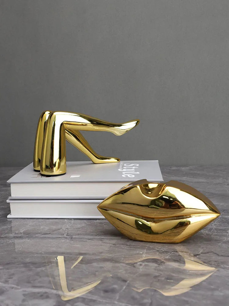 A gold faux finish sculpture of a human face or lips, displayed on stacked white books.