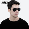 A man wearing black aviator-style sunglasses against a white background.