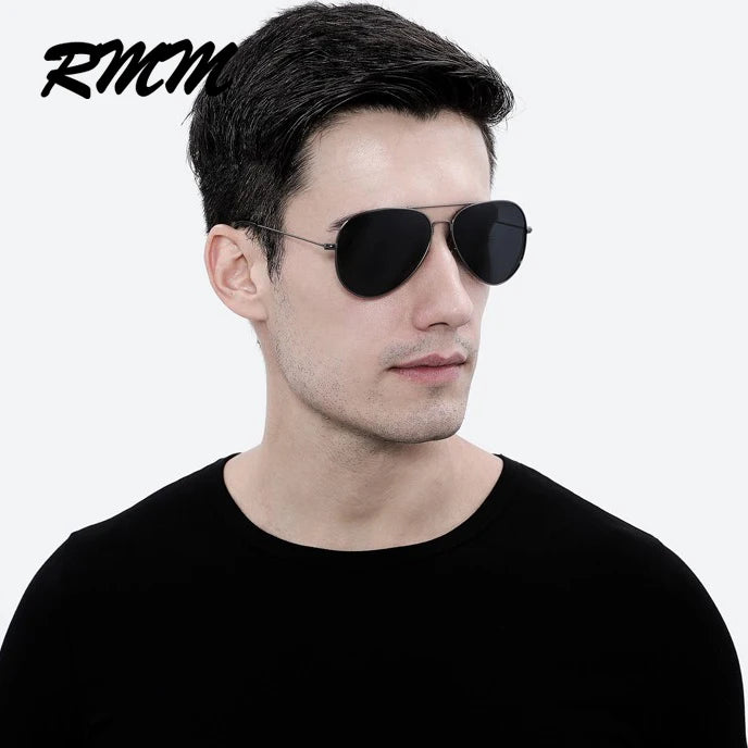 A man wearing black aviator-style sunglasses against a white background.